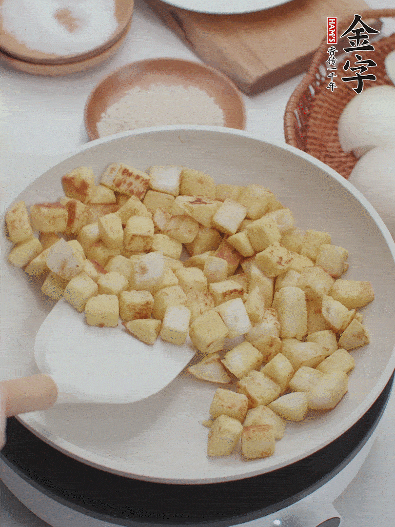起鍋熱油，倒入饅頭丁，小火煎至蛋液凝固定型再翻面，饅頭丁部煎至金黃時(shí)盛起待用。