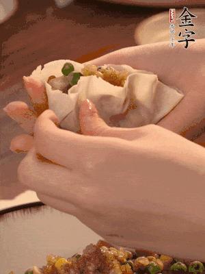 取一大勺餡料放進(jìn)餃子皮里，用大拇指按住頂部餡料，再用虎口掐出形狀。